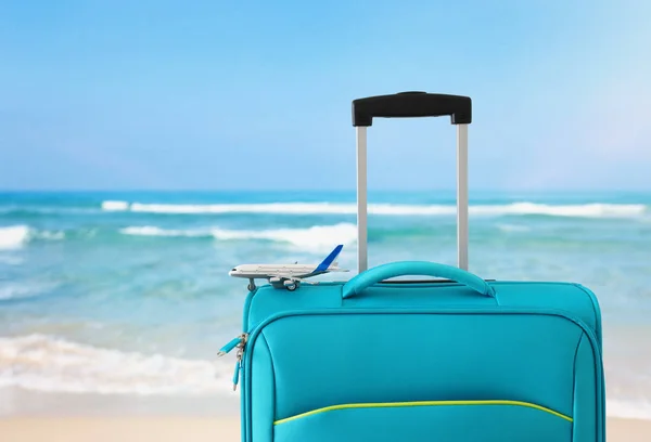 Vacances. concept de voyage. valise bleue et jouet d'avion devant fond de mer tropicale — Photo