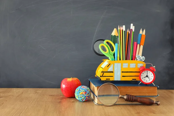 教育と学校の概念に戻る。鉛筆は教室の黒板の前の木製の机の上にバスとして立つ — ストック写真