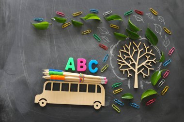 eğitim ve okul kavramına geri dön. Ahşap otobüs ve Abc harfleri üst görünüm fotoğraf, sınıf kara tahta arka plan üzerinde sonbahar yaprakları ile ağacın yanındaki çatıda kalemler. üst görünüm, düz yatıyordu