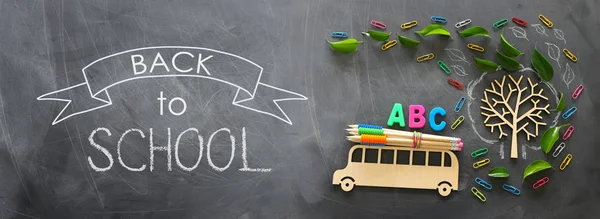 Éducation et concept de retour à l'école. Photo de dessus de bus en bois et lettres ABC, crayons sur le toit à côté de l'arbre avec des feuilles d'automne sur le fond du tableau noir de la classe. vue du dessus, plan plat — Photo