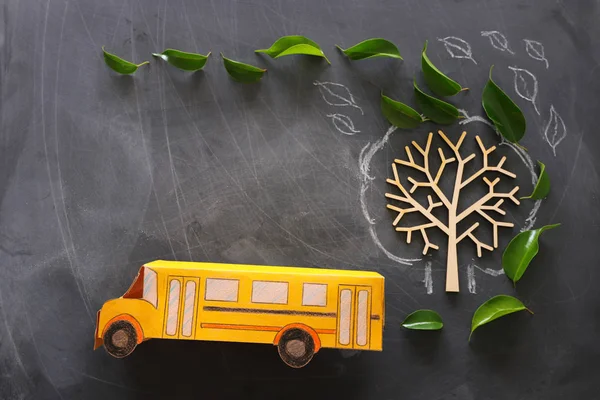 教育と学校の概念に戻る。教室の黒板の背景の上に秋の葉を持つ木の隣のスクールバスのトップビューの写真。トップビュー, フラットレイ — ストック写真