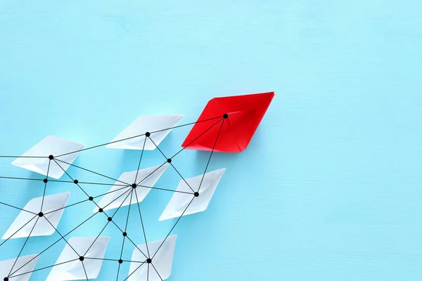 business. Leadership concept image with paper boats on blue wooden background. One leader guiding othes.