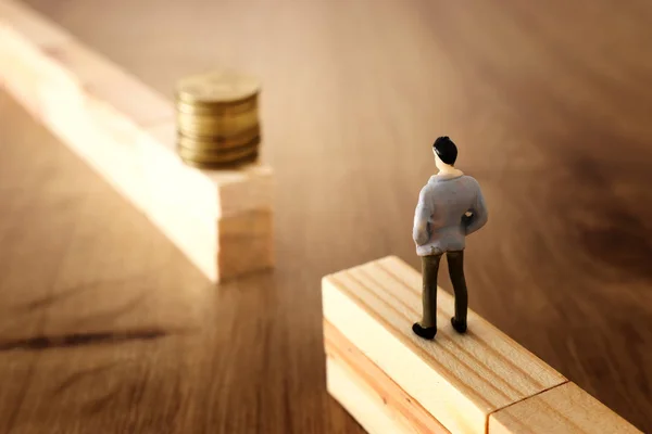 business concept image of challenge. A man stands on the edge of a gap and looks at a stack of coins, thinking how to earn more money