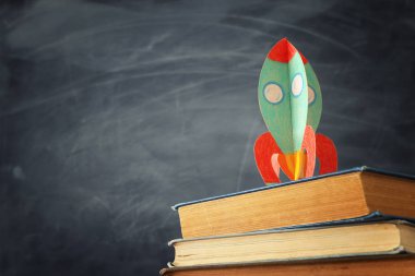 eğitim ve okul kavramına geri dön. sınıf tahta önünde kitaplar üzerinde karton roket