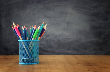 Eğitim ve okul konseptine geri dönüş. Sınıf tahtasının önündeki ahşap masanın üzerine kırtasiye kağıdı.