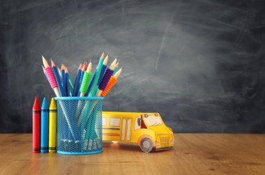 eğitim ve okul kavramına geri dön. sınıf tahta önünde kitap üzerinde karton otobüs ve kalemler