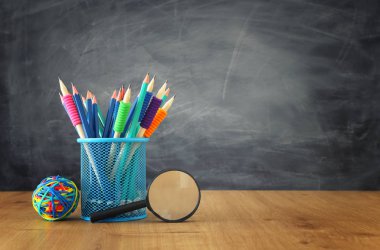 Eğitim ve okul konseptine geri dönüş. Sınıf tahtasının önündeki ahşap masanın üzerine kırtasiye kağıdı.