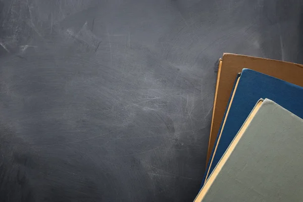 教育と学校の概念に戻る。黒板の前の木製の机の上に本の山。トップビュー, フラットレイ — ストック写真