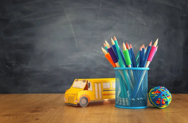 Εκπαίδευση και την επιστροφή στη σχολική έννοια. χαρτόνι λεωφορείο και μολύβια πάνω από τα βιβλία μπροστά από τον πίνακα τάξη — Φωτογραφία Αρχείου