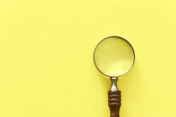 Vergrößerungsglas mit Holzgriff auf gelbem Hintergrund. Draufsicht, flache Lage — Stockfoto