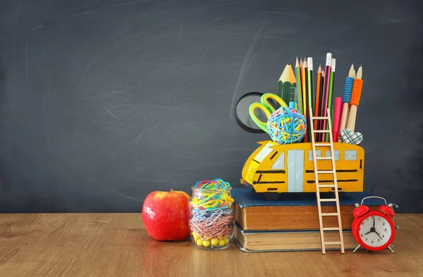 Образование и возврат к концепции школы. карандаши стоят как автобус над деревянным столом перед классной доской — стоковое фото