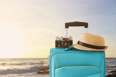 gezgin bagaj, kamera ve fedora şapka tropikal günbatımı arka plan önünde rekreasyon görüntü. tatil ve tatil konsepti