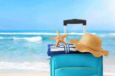 Tatil. seyahat konsepti. tropikal arka plan önünde kadın şapka, denizyıldızı ve plaj havlusu ile mavi bavul