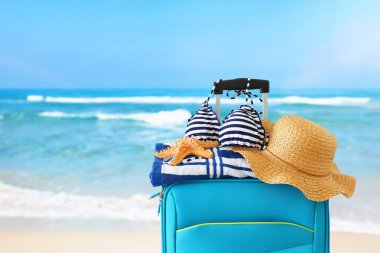Tatil. seyahat konsepti. tropikal arka plan önünde kadın şapka, denizyıldızı, bikini ve plaj havlusu ile mavi bavul