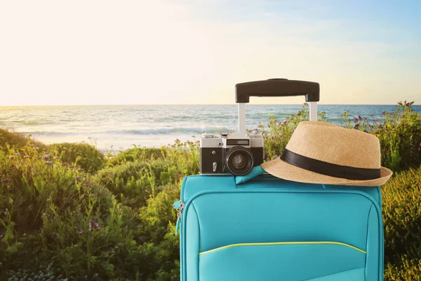 Recreation image of traveler luggage, camera and fedora hat infront of a rural lanscape. holiday and vacation concept — Stock Photo, Image