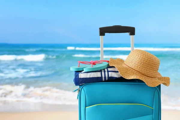 Vacances. concept de voyage. valise bleue avec chapeau féminin et serviette de plage devant fond tropical — Photo
