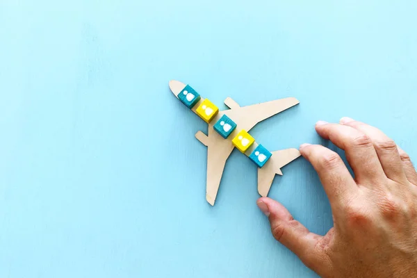 Imagem de conceito de transporte, mão do homem segurando avião de brinquedo com ícones de pessoas sobre fundo azul. Idéia de viagem e liderança — Fotografia de Stock