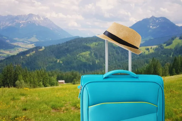 Rekreačním obrazem cestovních zavazadel a fedorského klobouku. před venkovskou krajinou. koncepce dovolené a dovolené — Stock fotografie