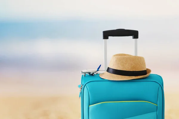 Feriados. conceito de viagem. mala azul e brinquedo de avião em frente ao fundo do mar tropical — Fotografia de Stock