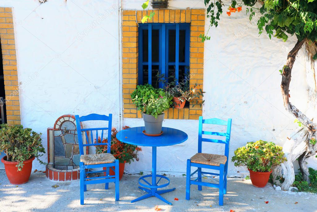 landmark photo of blue chairs with table in typical Greek town