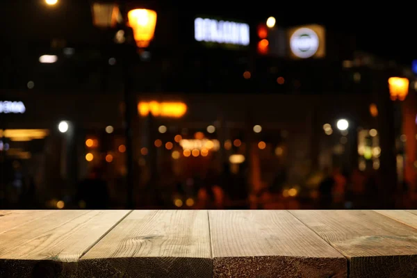 Imagem da mesa de madeira na frente de abstrato desfocado restaurante luzes fundo — Fotografia de Stock