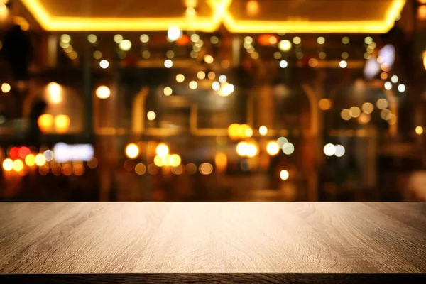 Image of wooden table in front of abstract blurred restaurant lights background — Stock Photo, Image