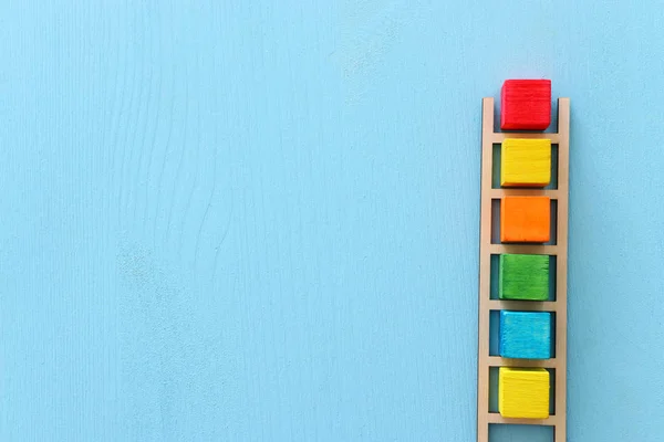 Business image of wooden ladder with colorful cubes over blue table, human resources and management concept — Stock Photo, Image