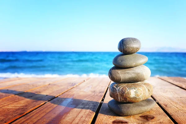 Steinpyramide auf Holzdeck über dem Strand symbolisiert Harmonie, Zen und Gleichgewicht — Stockfoto