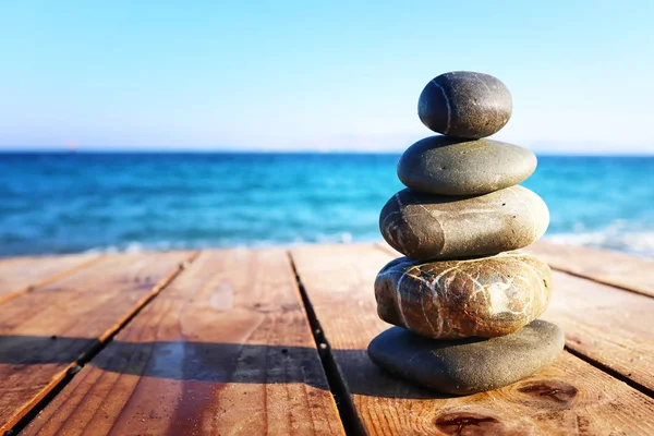 Pirâmide de pedras na praia deck de madeira simbolizando harmonia, zen e equilíbrio — Fotografia de Stock