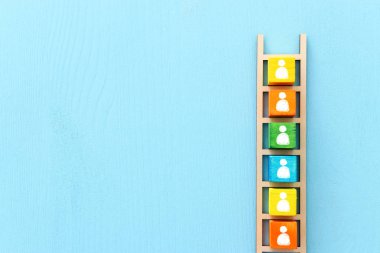 Mavi masa üzerinde insan simgeleri, insan kaynakları ve yönetim konsepti olan ahşap merdiven iş imajı