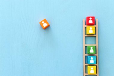 Mavi masa üzerinde insan simgeleri, insan kaynakları ve yönetim konsepti olan ahşap merdiven iş imajı