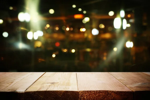 Background Image of wooden table in front of abstract blurred restaurant lights — Stock Photo, Image