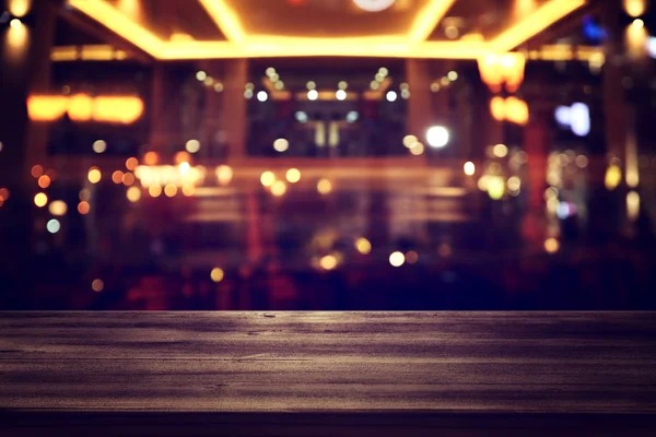 Background Image of wooden table in front of abstract blurred restaurant lights — Stock Photo, Image