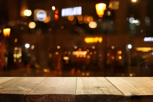 Hintergrund Bild eines Holztisches vor abstrakten verschwommenen Restaurantlichtern — Stockfoto