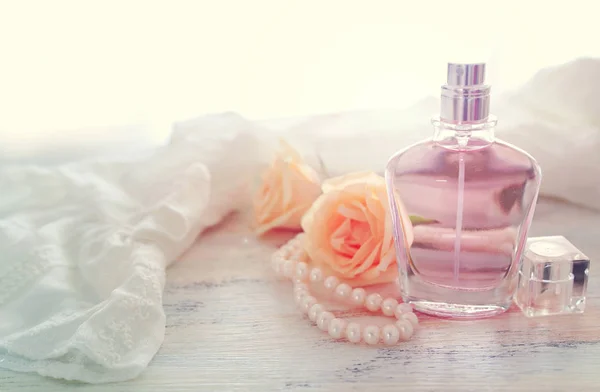 Szépség/divat kép az elegáns parfümös üveg, fehér gyöngy és finom Rózsa mint pasztell háttér. Vintage szűrt kép — Stock Fotó