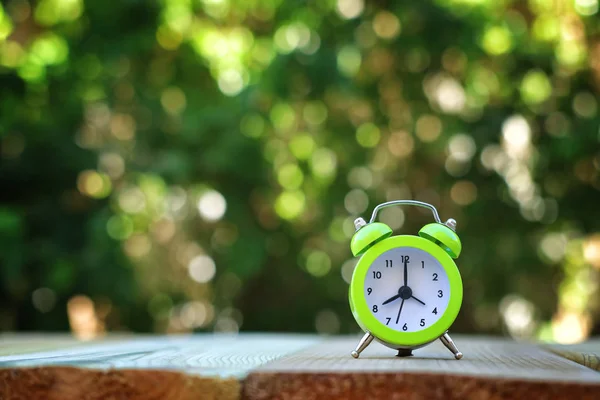 Imagen de otoño Cambio de Tiempo. Concepto de retroceso. Hojas secas y alarma vintage Reloj en mesa de madera al aire libre por la tarde —  Fotos de Stock