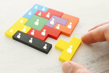 İnsanlar tahta masa, insan kaynakları ve yönetim kavramının üzerinde simgeler olan tangram bulmaca bloklarının iş konsepti imajı