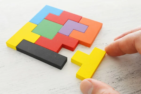 Imagem de conceito de negócio de um quebra-cabeça tangram quadrado colorido, sobre mesa de madeira — Fotografia de Stock