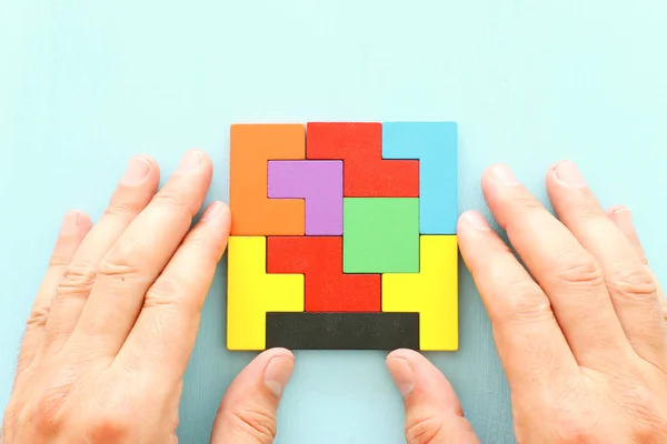 Imagem de conceito de negócio de um quebra-cabeça tangram quadrado colorido, sobre mesa de madeira — Fotografia de Stock