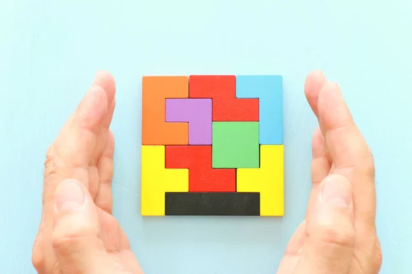 Imagem de conceito de negócio de um quebra-cabeça tangram quadrado colorido, sobre mesa de madeira — Fotografia de Stock