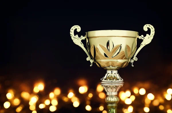 Conceito de esportes imagem chave baixa do troféu de ouro sobre fundo escuro, com luzes brilhantes abstratas — Fotografia de Stock