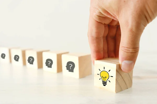 Business Concept image of revealing an idea, finding the right solution during creative process. Hand picking cube with bright light bulb — Stock Photo, Image