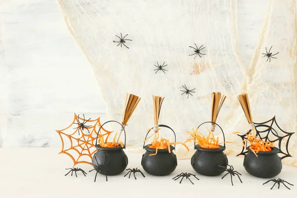 Vakantie foto van Halloween. Witcher ketel, bezem en spinnen over witte houten tafel — Stockfoto