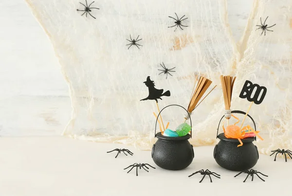 Vakantie foto van Halloween. Witcher ketel, bezem, snoepjes en spinnen over witte houten tafel — Stockfoto