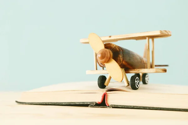 Oldtimer-Spielzeugflugzeug und das aufgeschlagene Buch auf Holztisch — Stockfoto