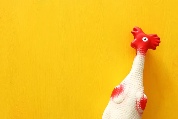 funny background of rubber chicken toy on yellow table