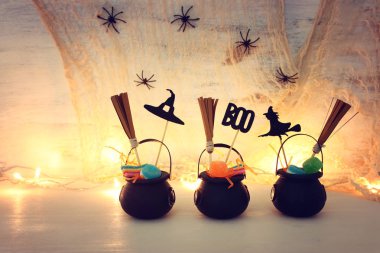 Cadılar Bayramı tatil görüntü. Witcher kazanı, süpürge, şekerler ve örümcekler beyaz ahşap masa üzerinde