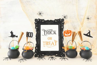 Cadılar Bayramı tatil görüntü. Witcher kazanı, süpürge, şekerler ve örümcekler beyaz ahşap masa üzerinde