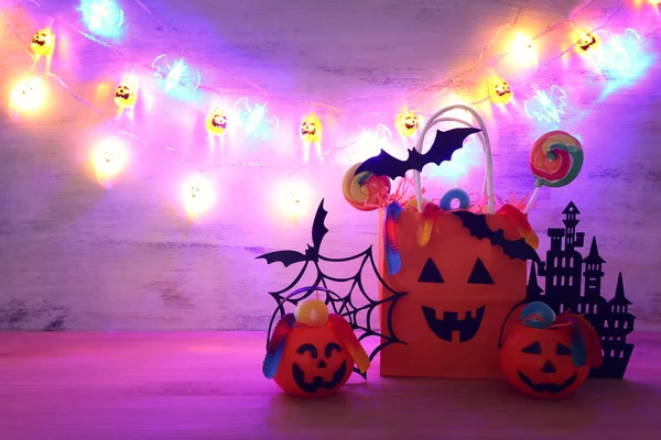 Vacances image de Halloween. Citrouilles, chauves-souris, friandises, sac cadeau en papier sur table en bois — Photo
