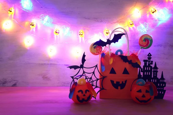 Urlaub Bild von halloween. Kürbisse, Fledermäuse, Leckereien, Papiergeschenktüte über Holztisch — Stockfoto